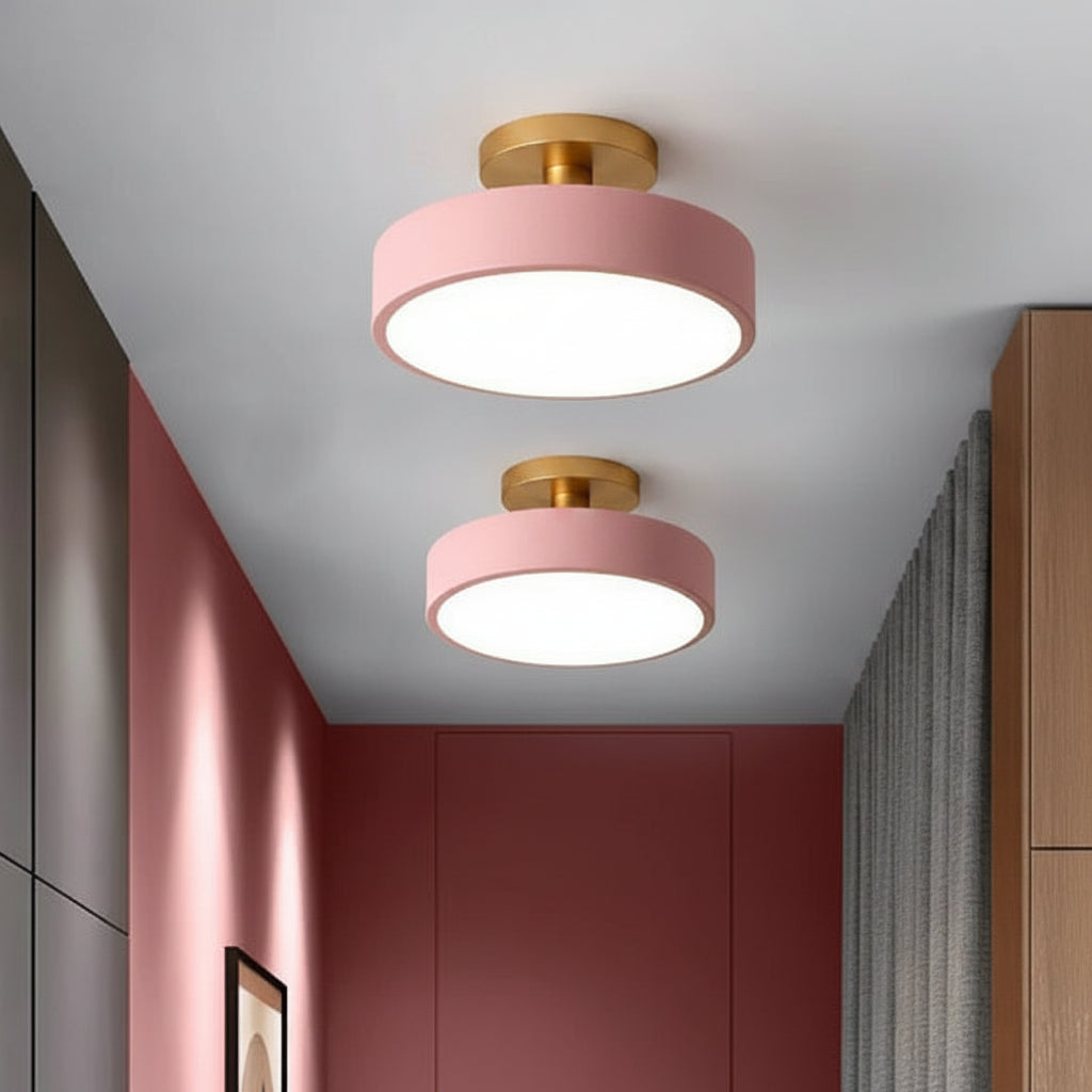 Two pink ceiling lights with wooden accents in a room with red walls and wooden furniture.